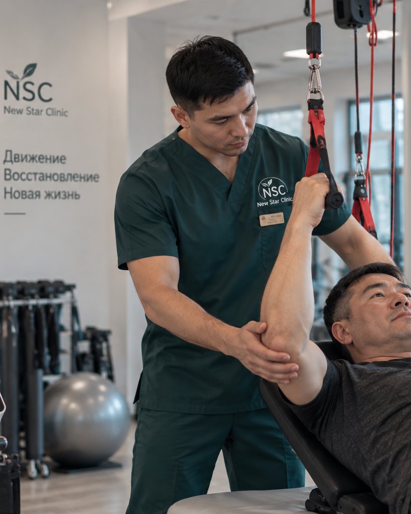 Специалист New Star Clinic проводит реабилитацию пациента на тренажёре